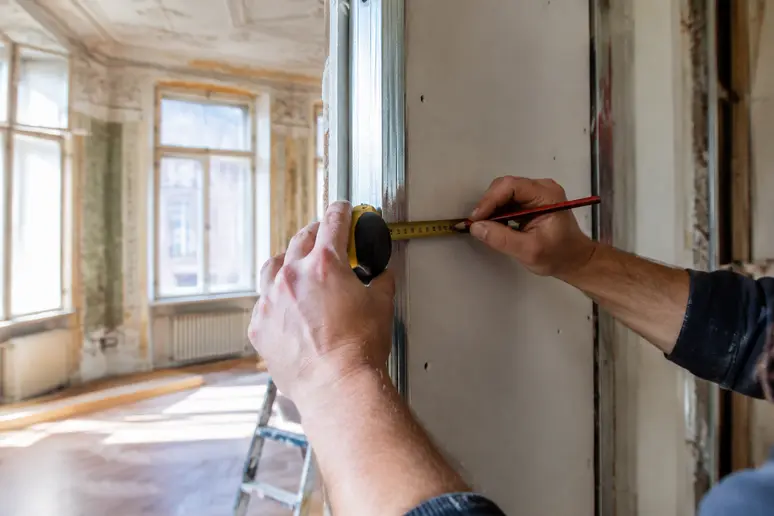 Mains mesurant une cloison lors d'une rénovation d'appartement niçois ancien