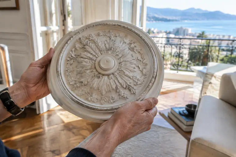 Mains examinant des moulures anciennes de plafond pour conserver le cachet d un appartement à Cannes