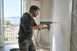 Un artisan portant des protections auditives utilise une perceuse lors des horaires travaux appartement nice autorisés