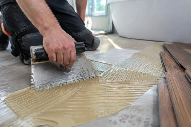 Application de colle polyuréthane au peigne pour la pose d'un parquet salle de bain