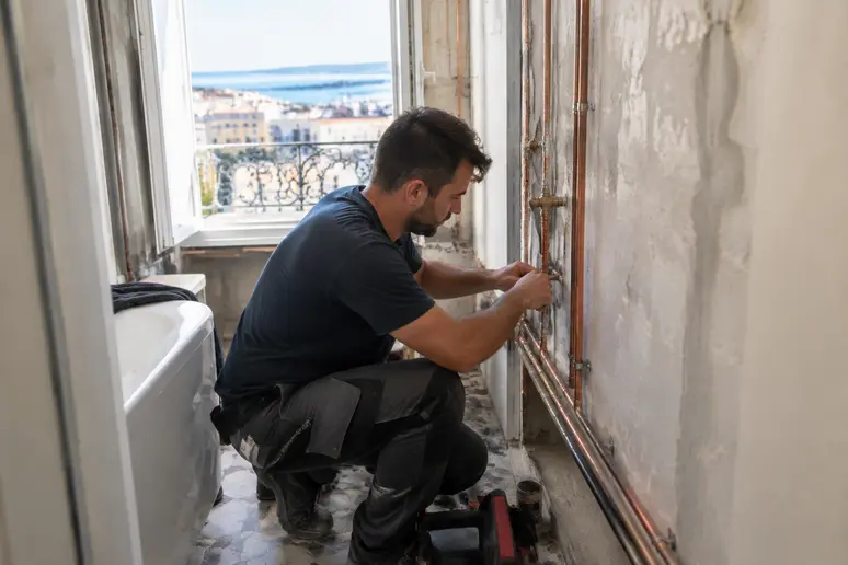 artisan plombier installant la tuyauterie d'une petite salle de bain à rénover dans les Alpes-Maritimes