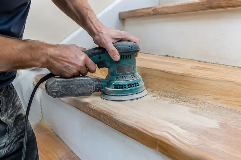 Ponçage électrique d'une marche en bois lors d'une rénovation d'escalier